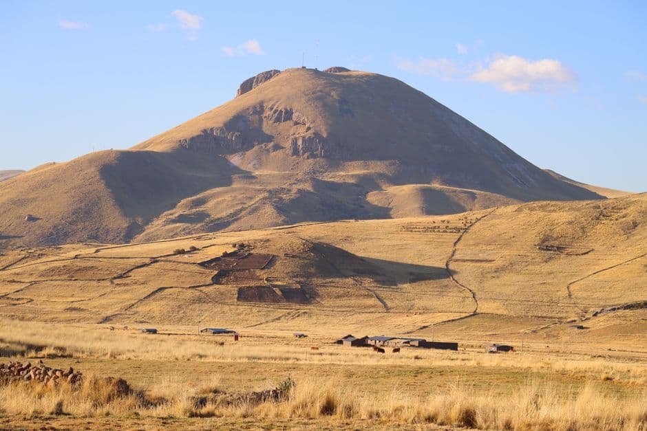 Scenic view of the Andean mountains and grasslands under a clear blue sky in Peru.