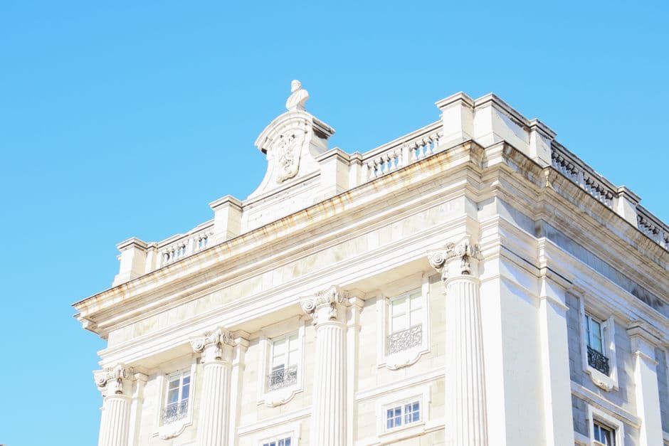 Detailed view of a neoclassical building facade against a bright blue sky.