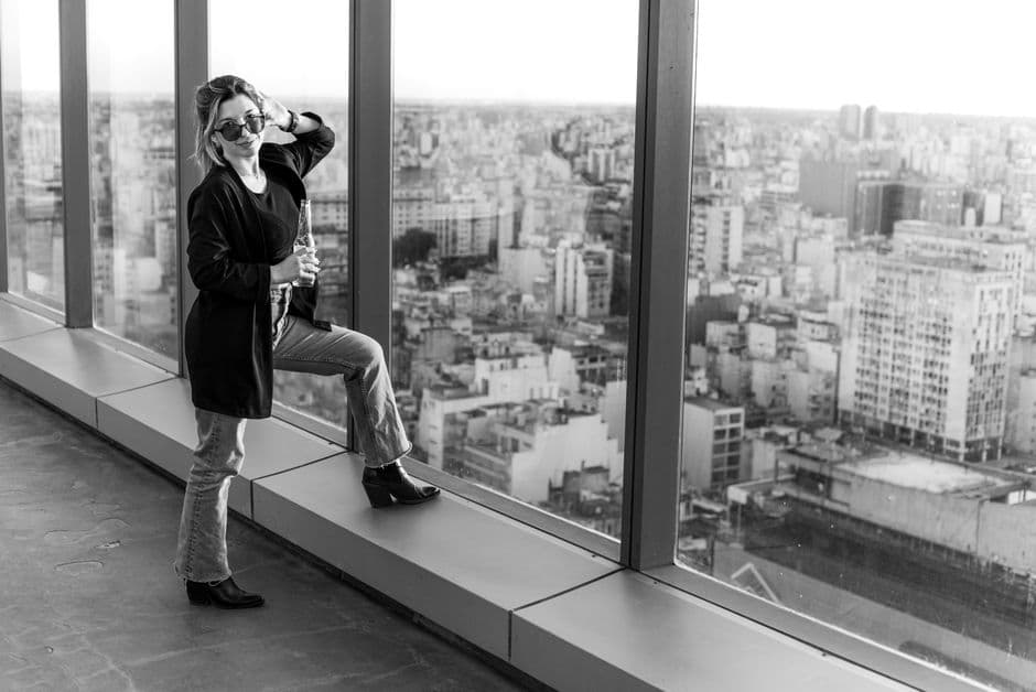 Elegant woman posing by the window with Buenos Aires cityscape in the background.