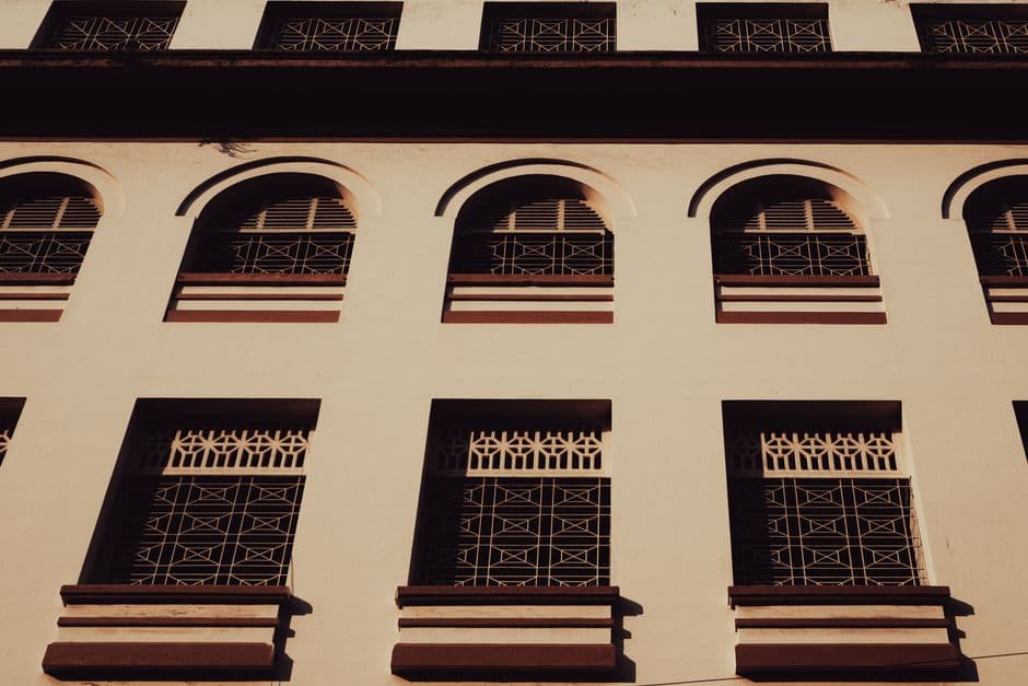 Facade of a vintage building featuring arched windows and intricate grillwork.