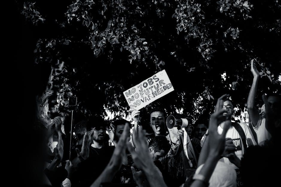 A protest scene with diverse individuals, emphasizing unemployment issues in black and white.