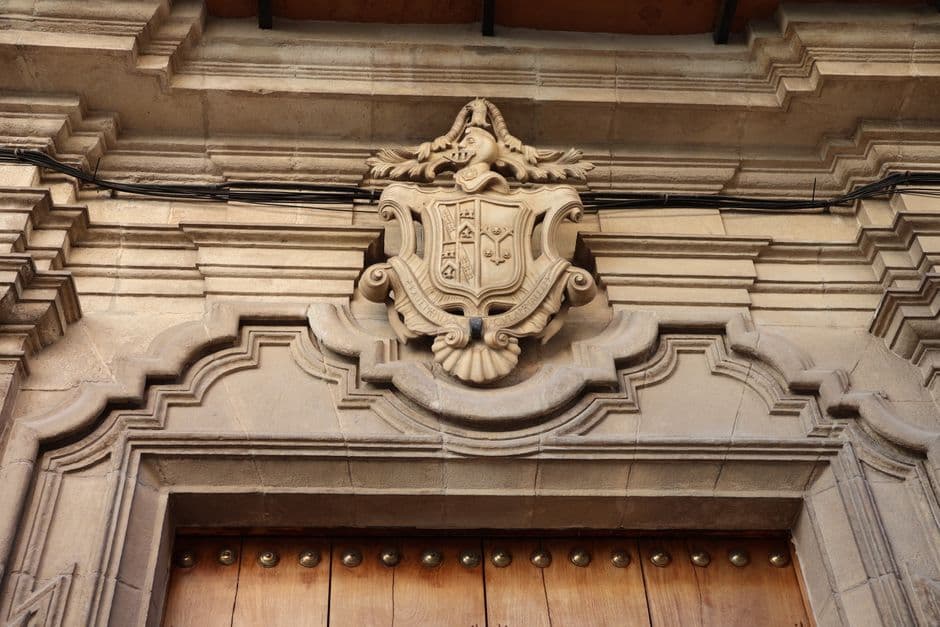 Close-up of a historic stone emblem on a building facade in El Puerto de Santa María, Spain.
