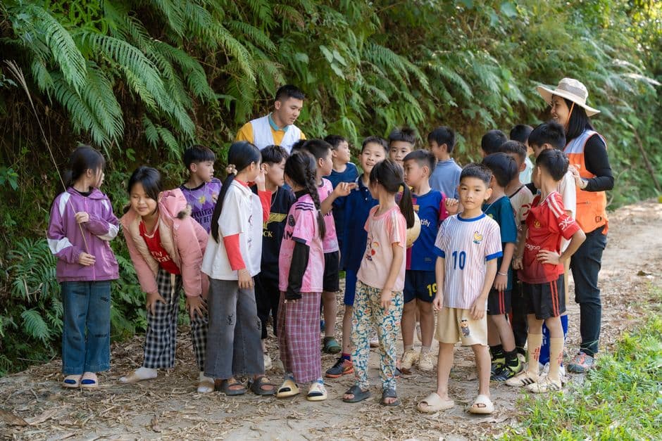 Group of children engaged in outdoor learning activity on a nature trail with two adult guides.