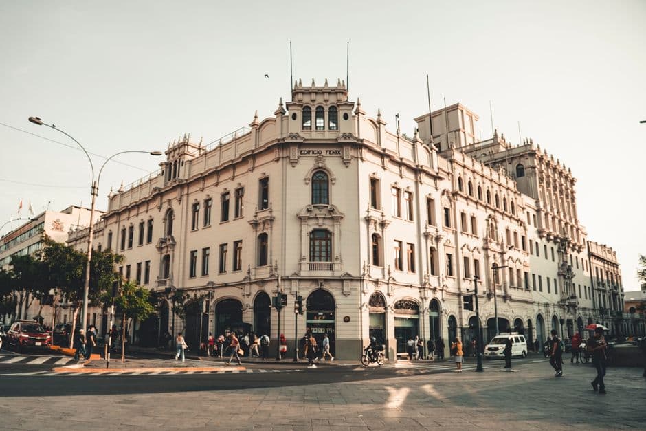 Historic Edificio Fenix with pedestrians in a bustling city street at sunset, showcasing classical architecture.