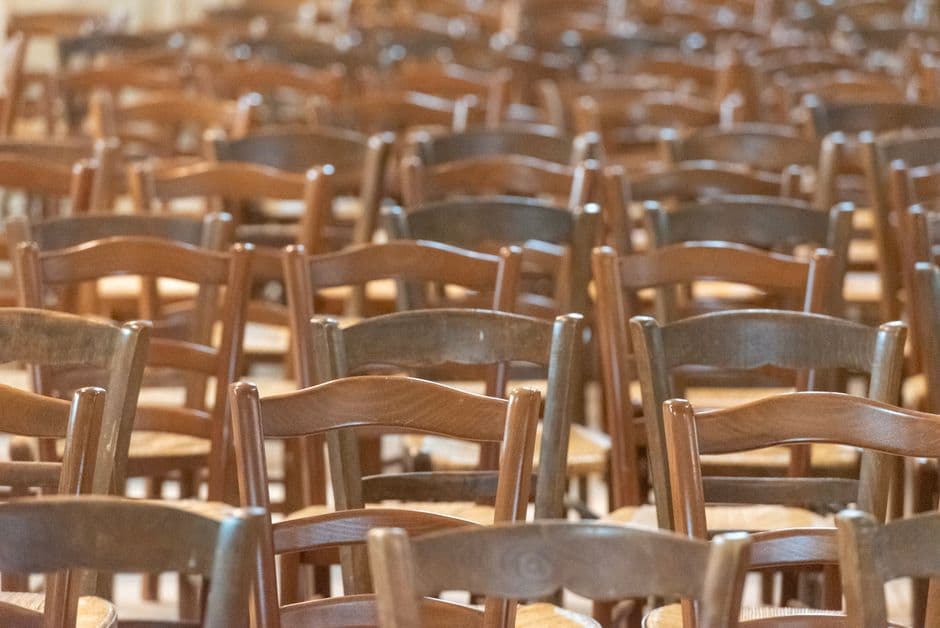 Rows of wooden chairs in a church with soft lighting, creating a warm atmosphere.
