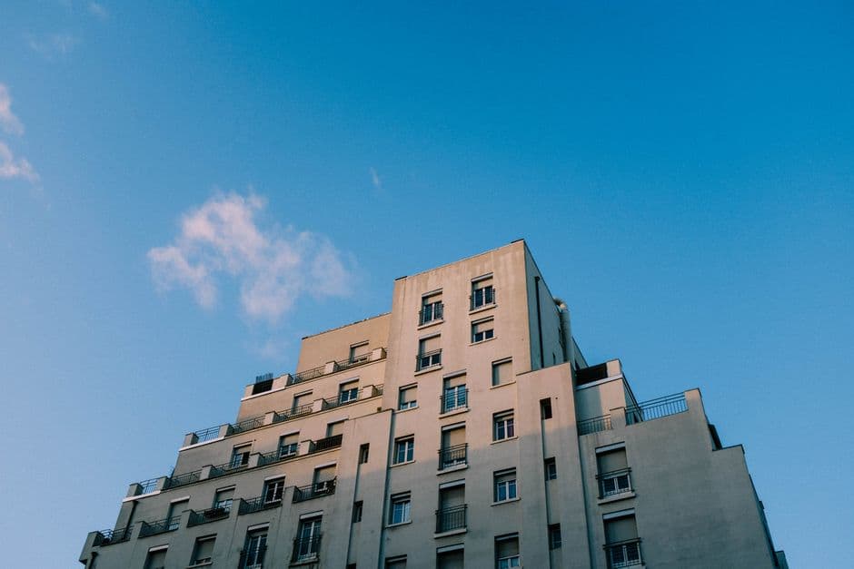 Low-angle shot of a modern apartment building with a clear blue sky.