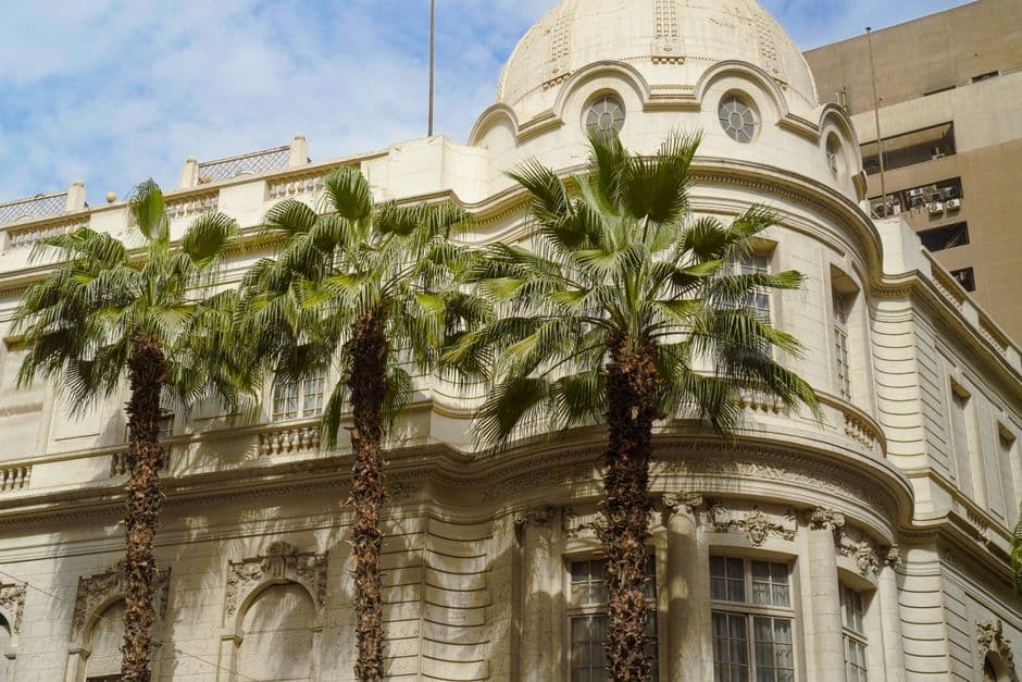 Historic building in Cairo, Egypt, with beautiful palm trees and a clear blue sky.