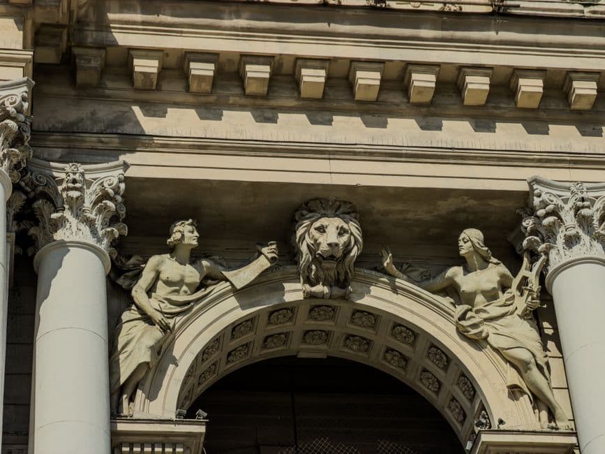 Close-up of architectural sculptures on an Italian building featuring classical figures and a lion.
