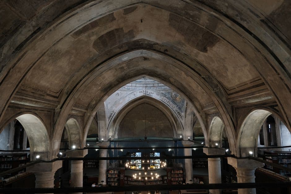 Intricate Gothic arches inside a historic library creating a majestic atmosphere.