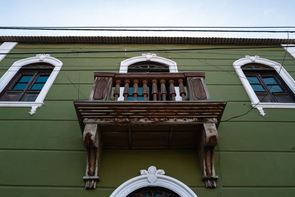 Upward view of historic colonial architecture featuring a wooden balcony in Pacasmayo, Perú.