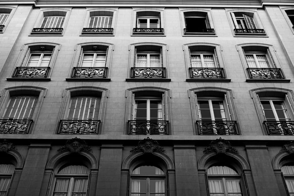 Monochrome image of a classic building facade in Buenos Aires, showcasing detailed ironwork and arched windows.
