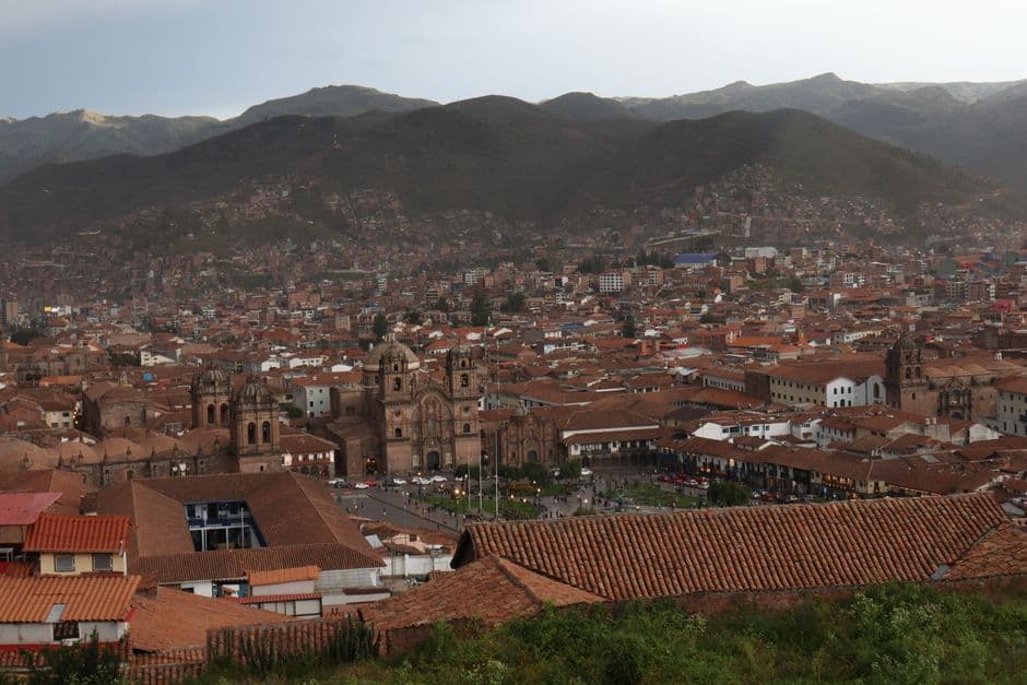 Scenic aerial view of Cuzco, Peru with mountains in the background and historic architecture.