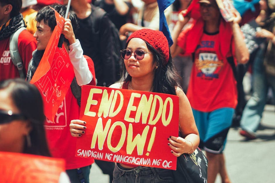 Group of protesters marching outdoors holding a vibrant sign demanding end of contractualization.