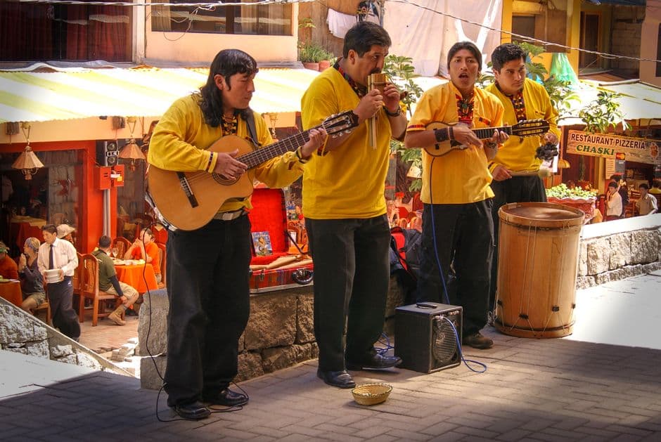 Andean musicians performing with traditional instruments on a street in Cusco, Peru.