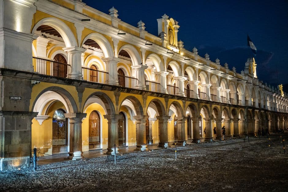 Night view of the illuminated colonial building Arco de Santa Catalina in Antigua Guatemala, showcasing vibrant arches.