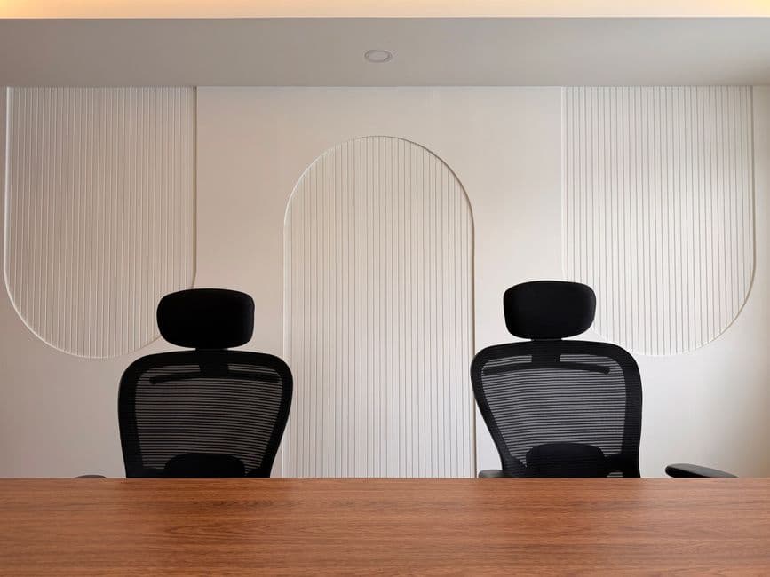 Stylish office space featuring two black ergonomic chairs and minimalist wall patterns.