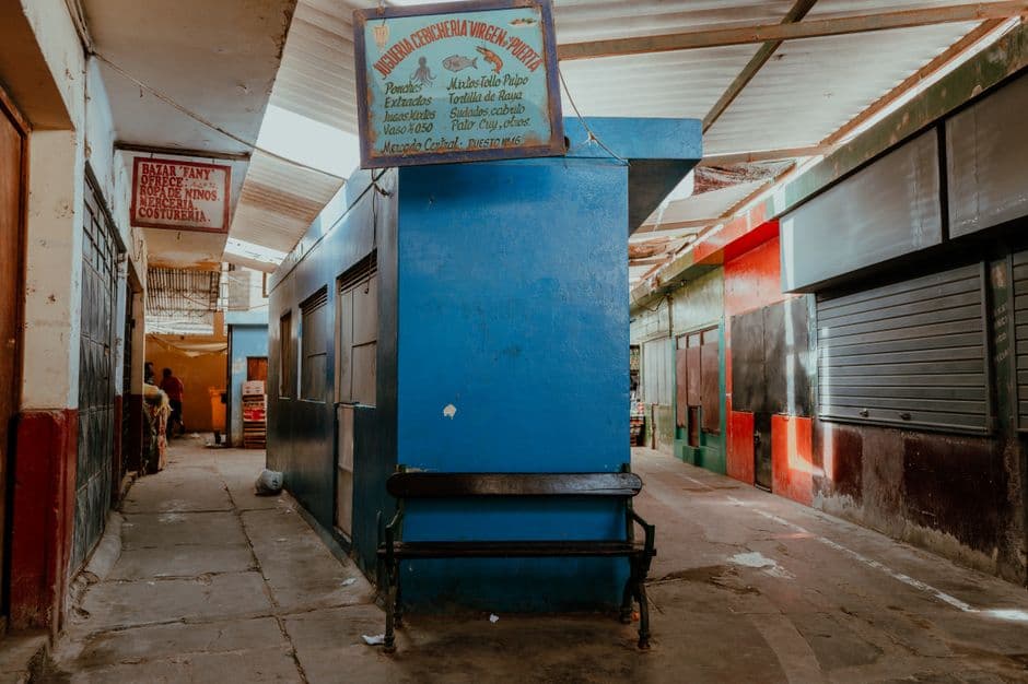 A quiet and colorful market corridor in Pacasmayo, Peru, showcasing vibrant walls and signs.