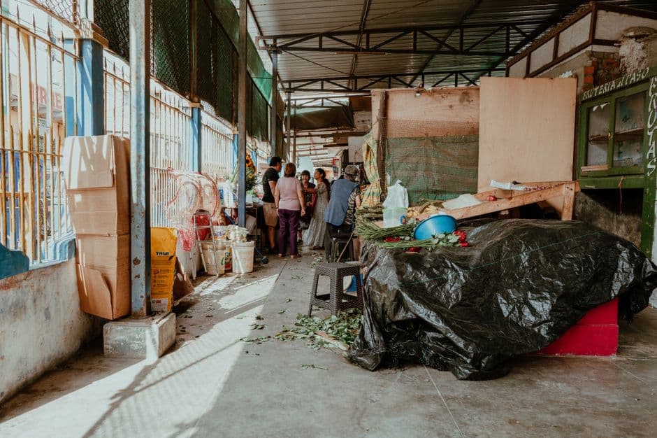 Indoor market in Pacasmayo, Peru with people interacting amid vibrant goods and natural lighting.
