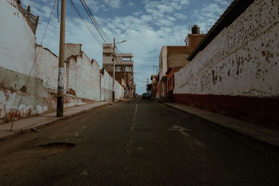 Explore a deserted street lined with rustic buildings in Pacasmayo, Peru, under a blue sky.