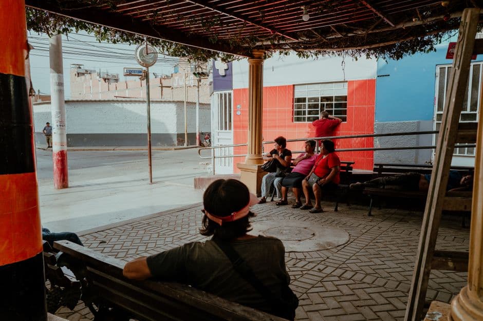 A group of locals relaxing under a shaded area in Pacasmayo, Peru, capturing a typical street scene.
