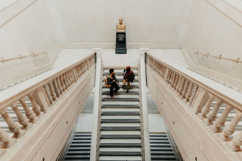 Two university students walking on a grand staircase in Buenos Aires, Argentina, indoors.