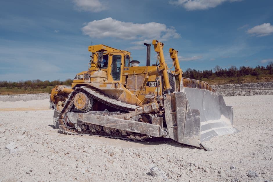 A yellow bulldozer operates in a quarry under a blue sky, showcasing industrial strength.