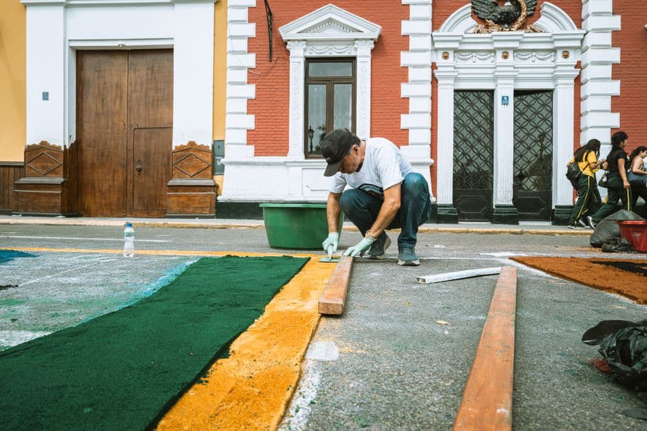 Artist crafting vibrant street art outside historic Peruvian architecture in Trujillo.