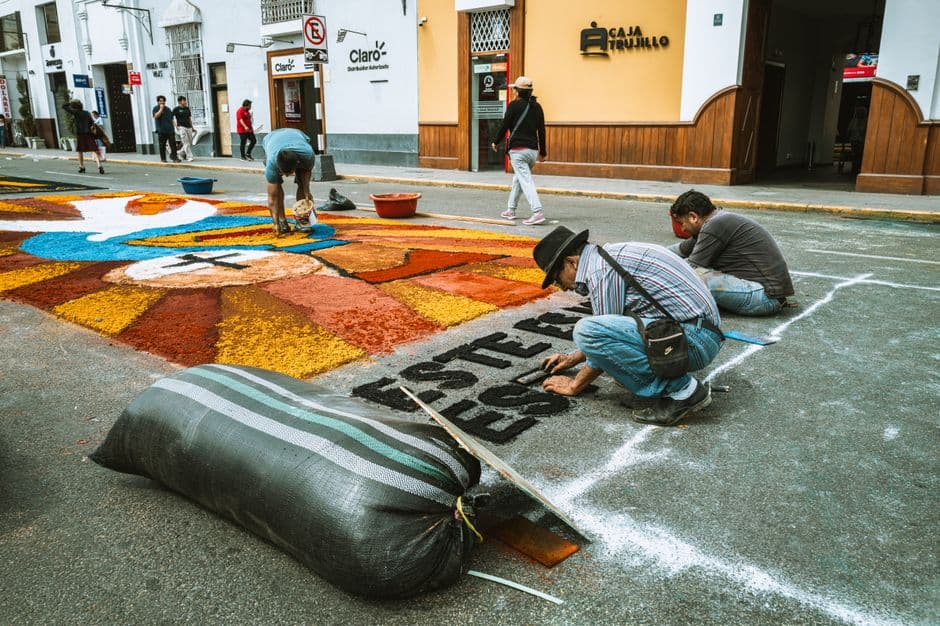 Artists creating colorful sawdust artwork on the street in Trujillo, Peru.