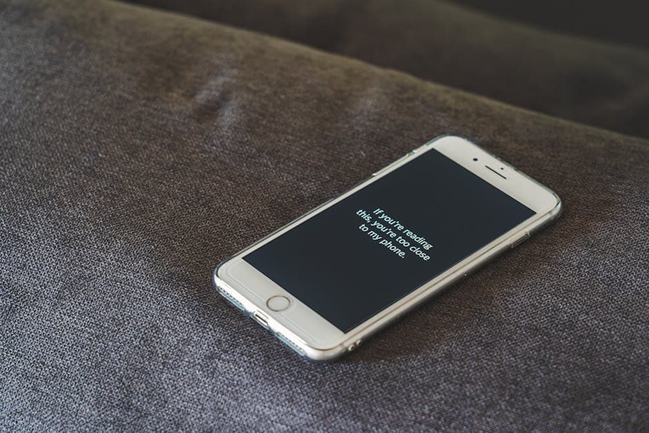 A smartphone with a humorous lock screen message placed on a grey couch, emphasizing privacy.