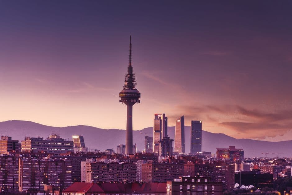 Stunning view of Madrid's skyline at twilight featuring the iconic Torrespaña Tower and mountains in the background.