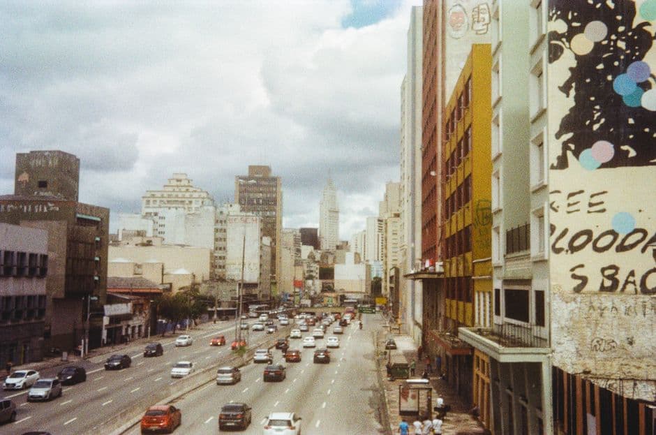 High angle view of a bustling city street with traffic and skyscrapers under cloudy skies.