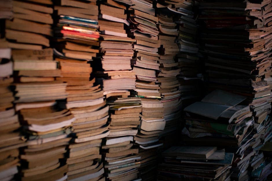 A large collection of stacked vintage books fills a dimly lit room, symbolizing knowledge and literature.