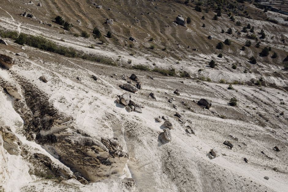 A rugged, barren mountain slope featuring scattered rocks and sparse vegetation.