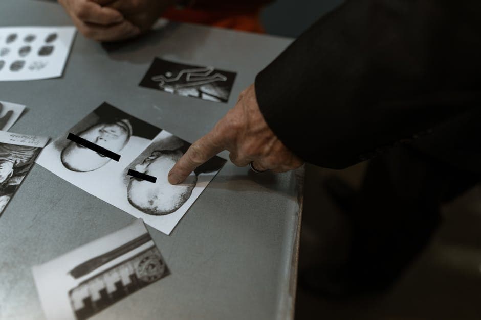 Detective reviewing crime scene photos and fingerprints indoors.