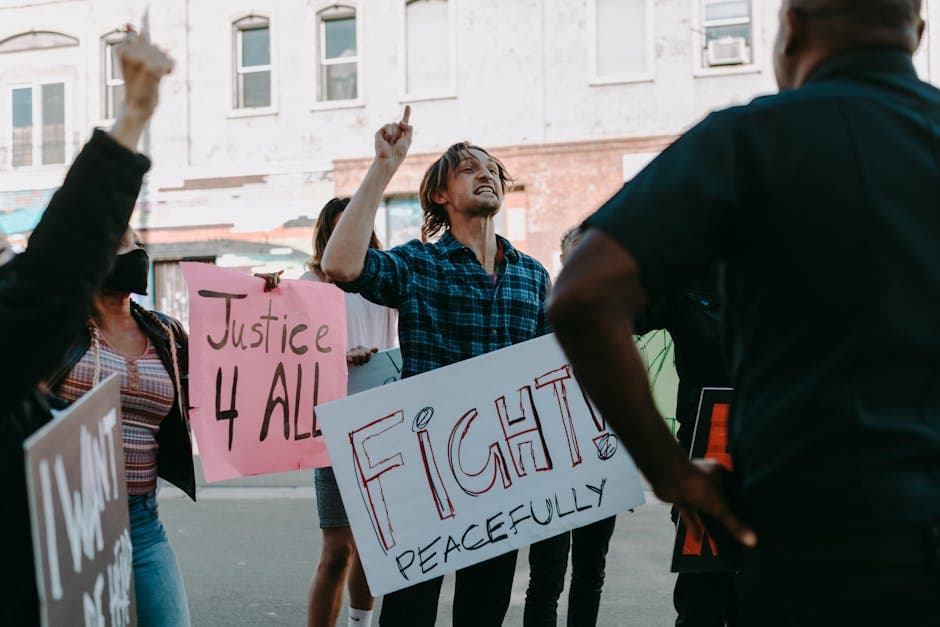 Protesters holding signs for justice and peace during a daytime demonstration outdoors.