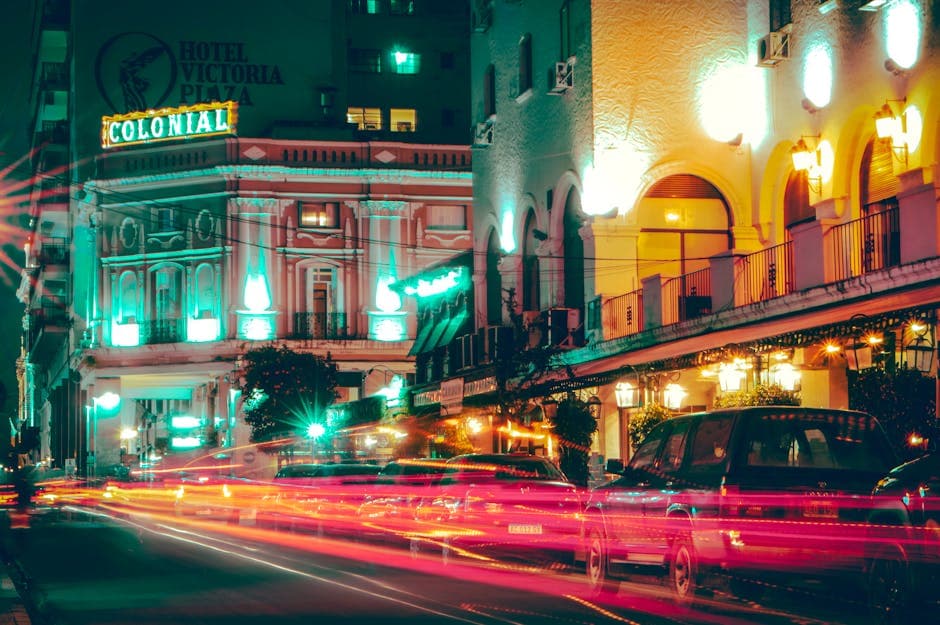 Neon-lit street scene showcasing light streaks and urban nightlife atmosphere with colonial architecture.