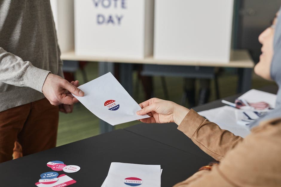 Two people exchanging a ballot paper during an indoor voting process.