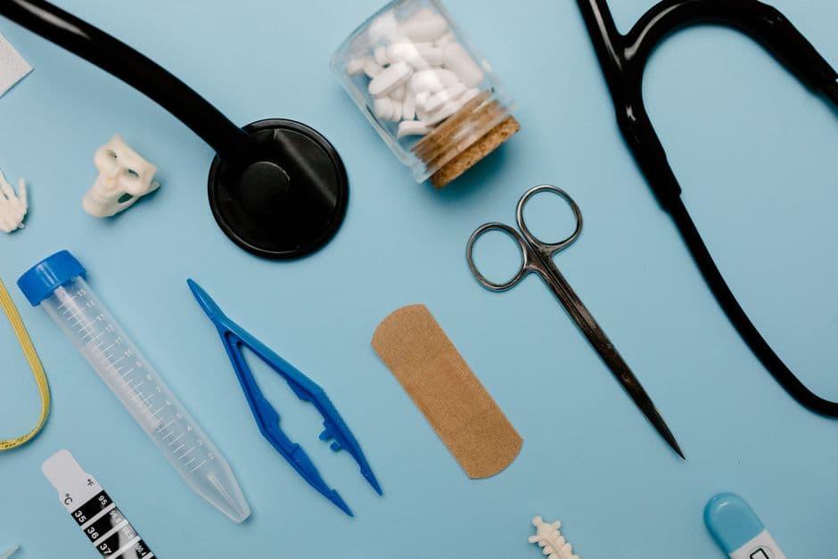 Flat lay of assorted medical tools and equipment on a blue surface.
