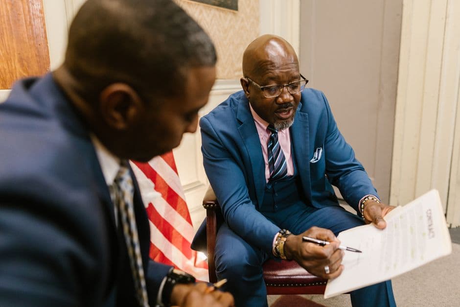 Two businessmen reviewing a contract document in an office setting.