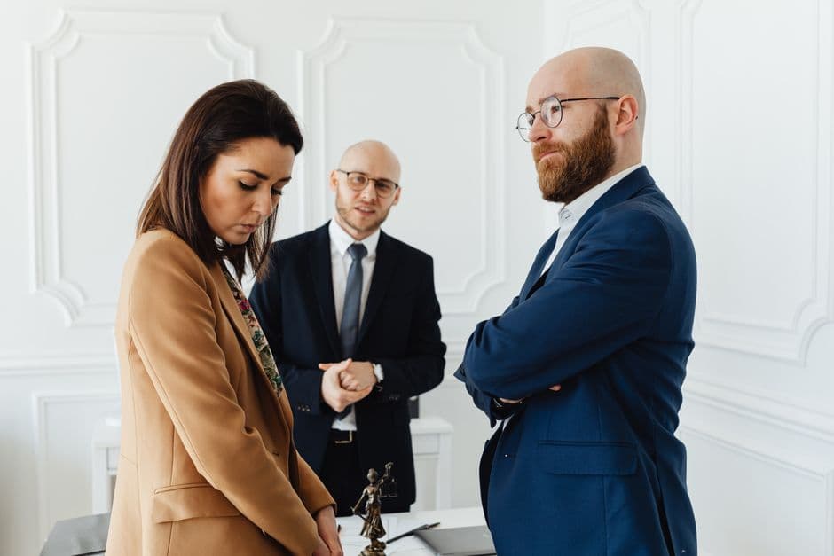 Lawyers discussing case indoors with clients in formal office attire.