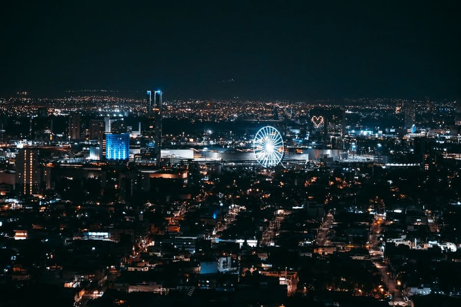 Stunning nighttime aerial view of Puebla city's illuminated skyline featuring a Ferris wheel.