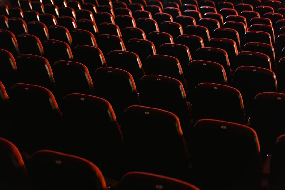 A view of empty red theater seats lit softly, showcasing the quiet ambiance of a cinema.