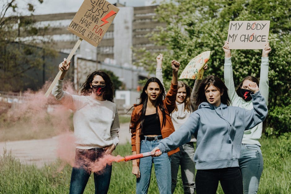 Group of women protesting with placards and smoke flares outdoors.