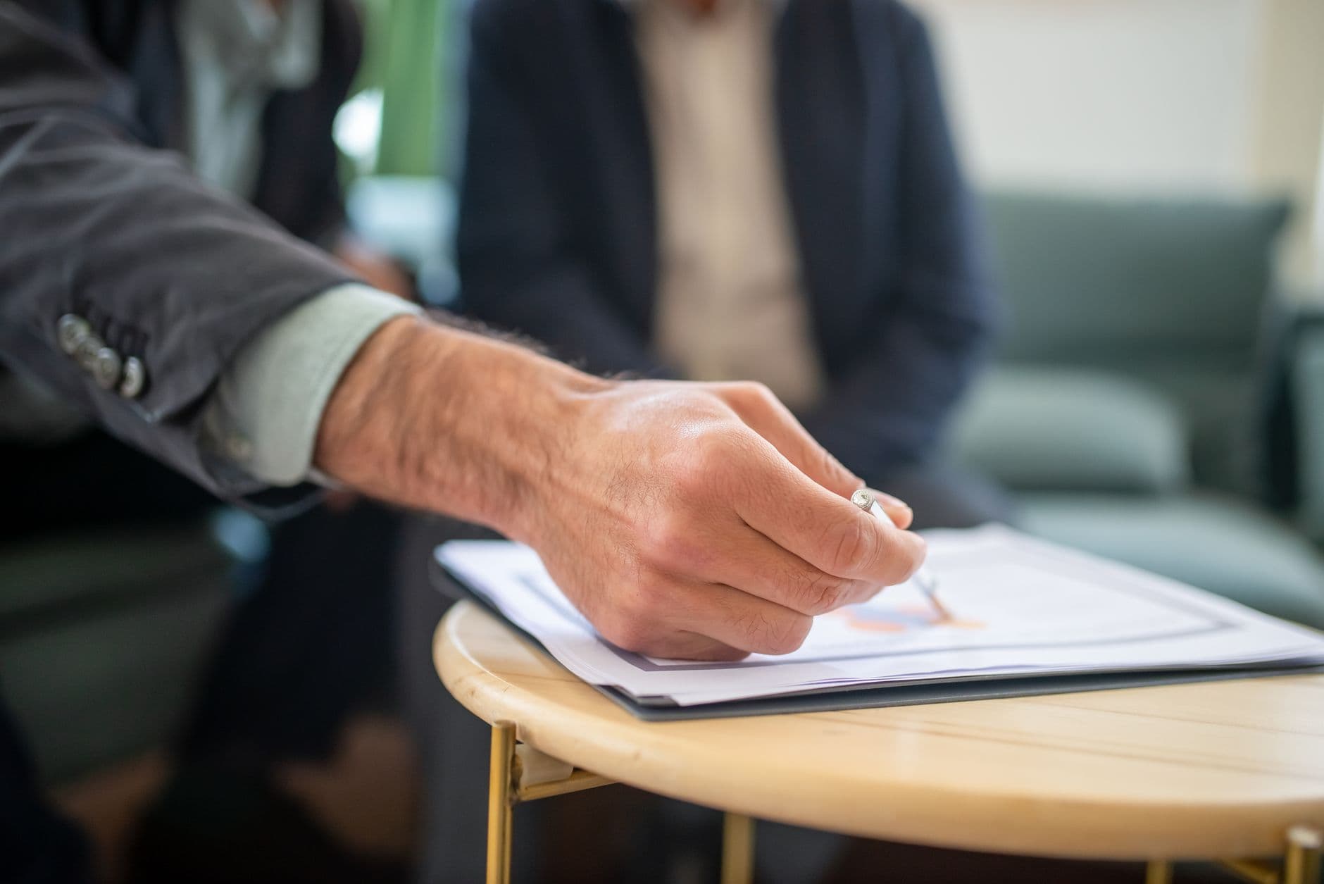Close-up of a professional during a business meeting, focusing on documents and writing.