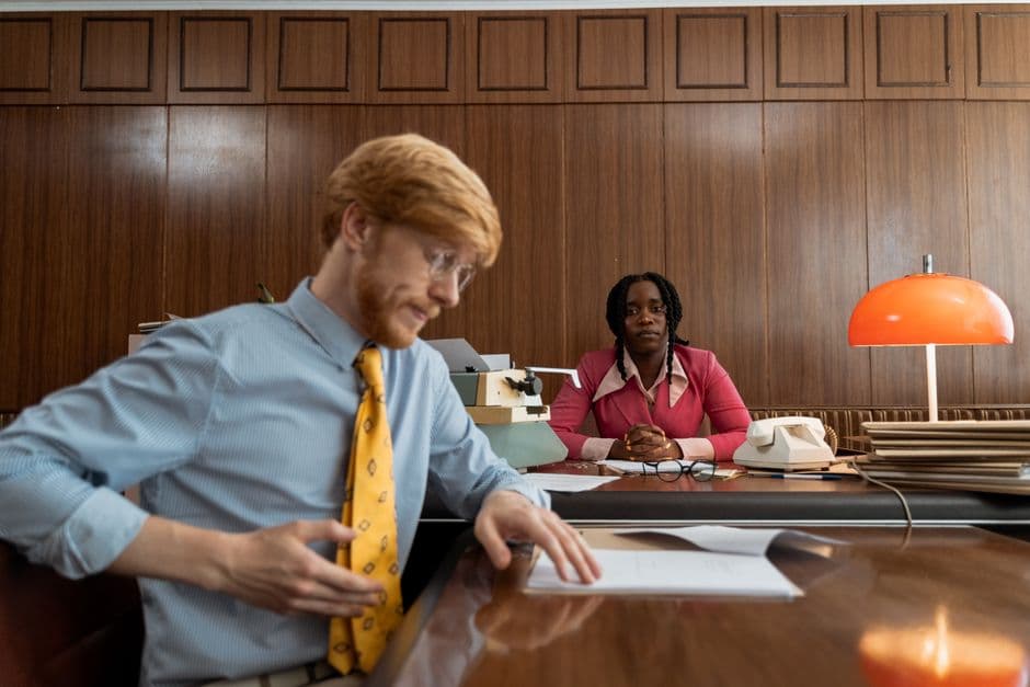 Two professionals engaged in a serious office meeting with vintage decor and typewriter.