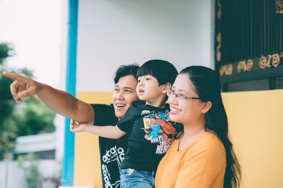 Asian family enjoying togetherness outdoors, pointing at something with smiles.