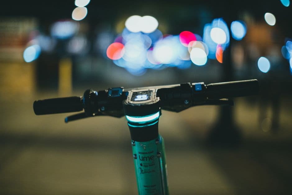 Close-up of electric scooter handlebars at night with a beautiful bokeh background, creating a city vibe.