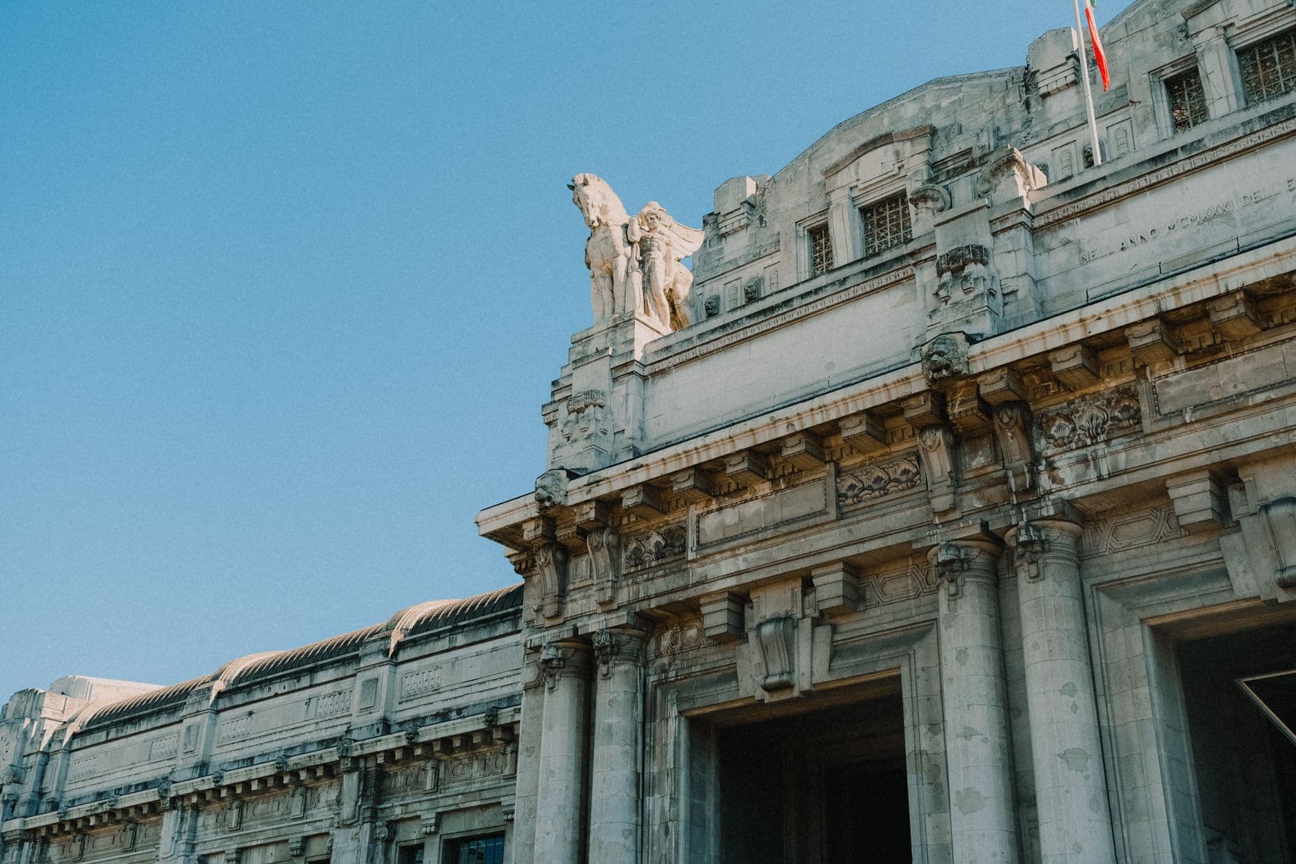 Low-angle view of a historic stone building with ornate sculptures and clear blue sky background.