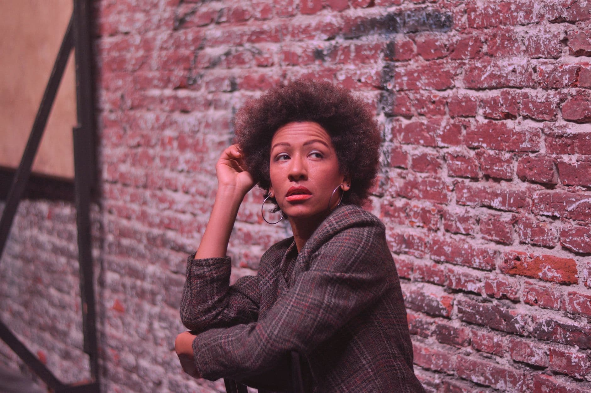 A fashionable woman posing by a brick wall in Mar del Plata, showcasing urban chic style.