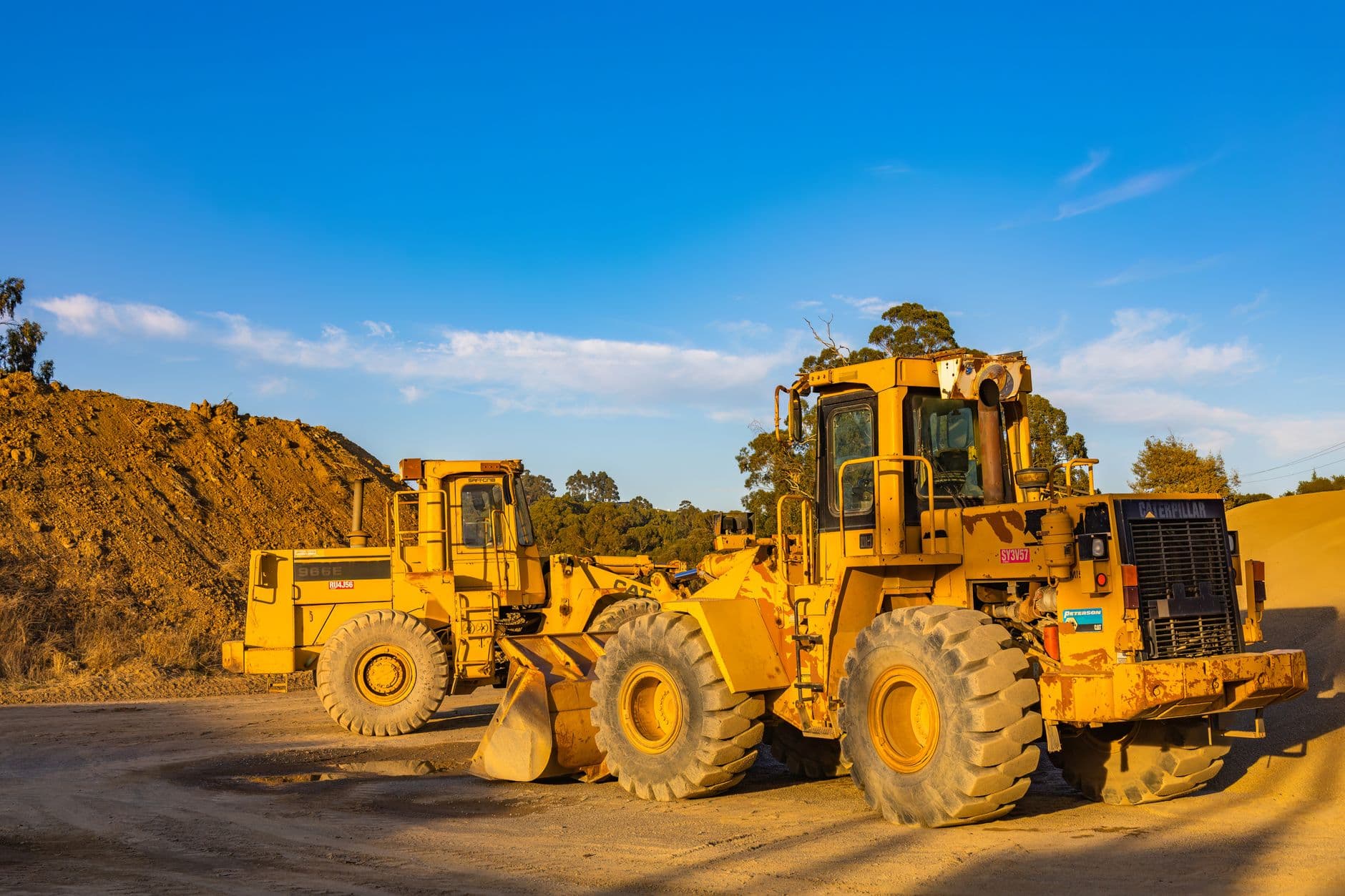 Heavy-duty bulldozers parked at a construction site under bright blue skies, showcasing industrial machinery.